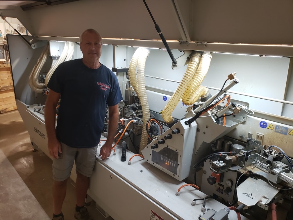 Chris Peterson standing beside a Biesse edgebander open for service